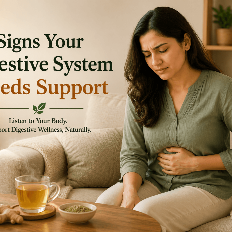 Person sitting on a couch with a hand on their stomach and a cup of ginger tea nearby, illustrating early signs that the digestive system may need support in a calm home setting.